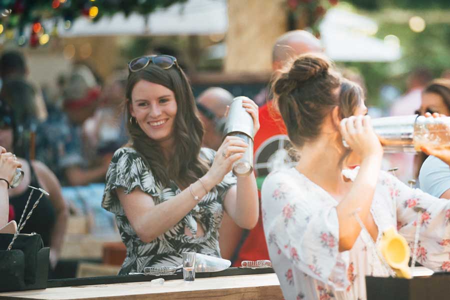 Two women making cocktails outside at a hen party
